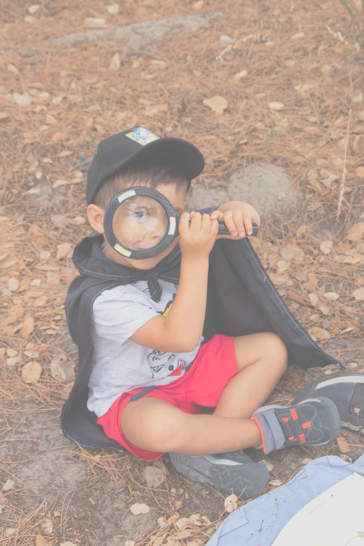 Child observing nature up close with a magnifying glass
